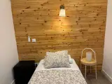 Televisor de pantalla plana sobre un escritorio blanco con silla negra junto a la ventana